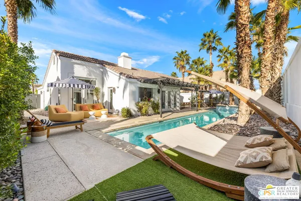 a view of a patio with couches table and chairs with potted plants and wooden fence