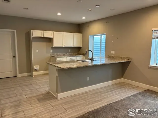 a kitchen with kitchen island granite countertop a sink window and cabinets