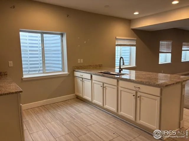 a kitchen with granite countertop a sink cabinets and wooden floor