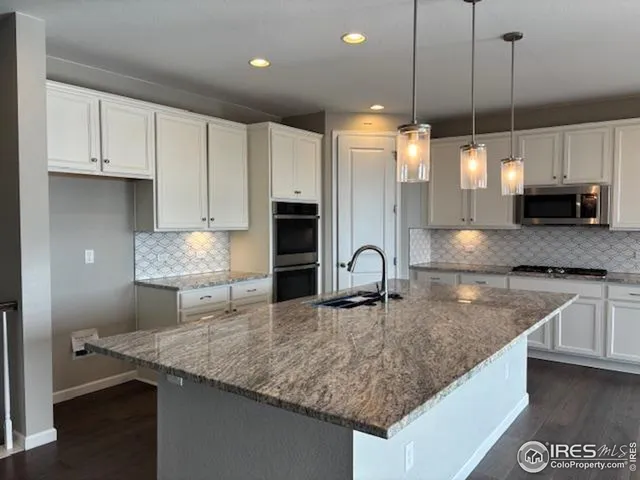 a kitchen with kitchen island granite countertop a sink a counter top space appliances and cabinets