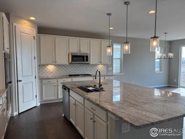 a kitchen with stainless steel appliances granite countertop a sink a stove and a refrigerator