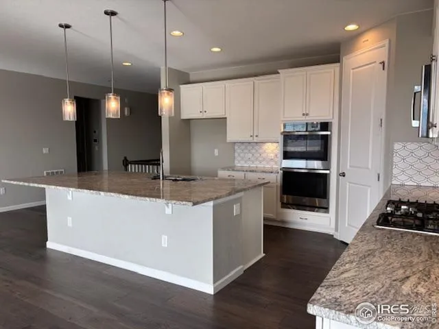a kitchen with kitchen island granite countertop a stove a sink and a wooden floors