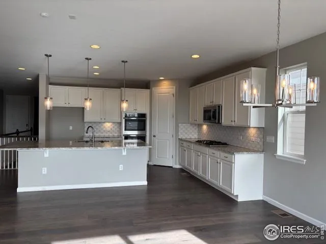 a large kitchen with stainless steel appliances kitchen island a large counter top and a wooden floors