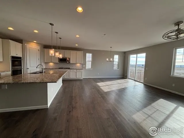 a view of kitchen with kitchen island granite countertop wooden floor stainless steel appliances and cabinets