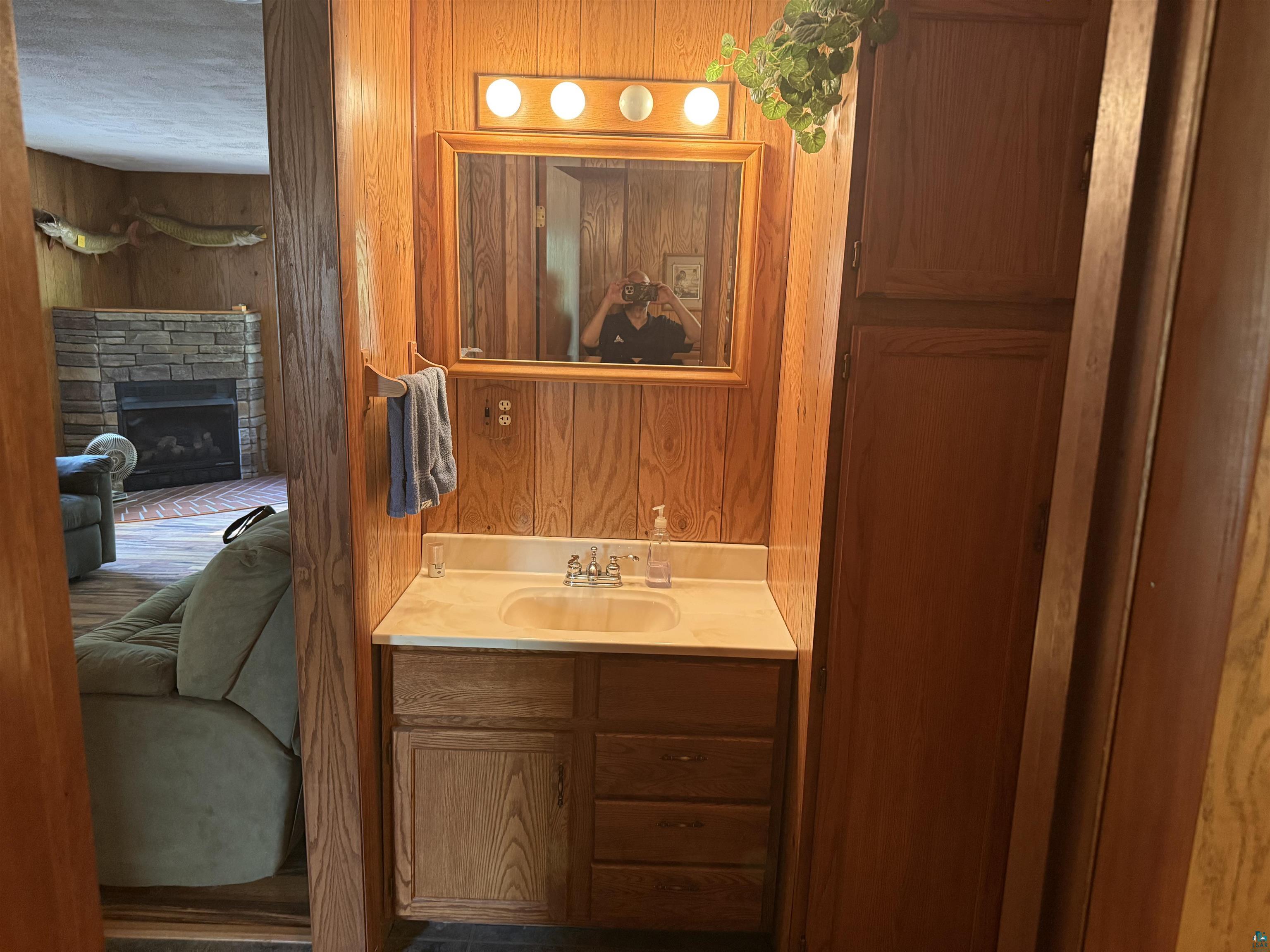 63380 Trout Lake Road Iron River, WI 54847 - Photo 28 of 36 Bathroom featuring wooden walls, a stone fireplace, vanity, and a textured ceiling