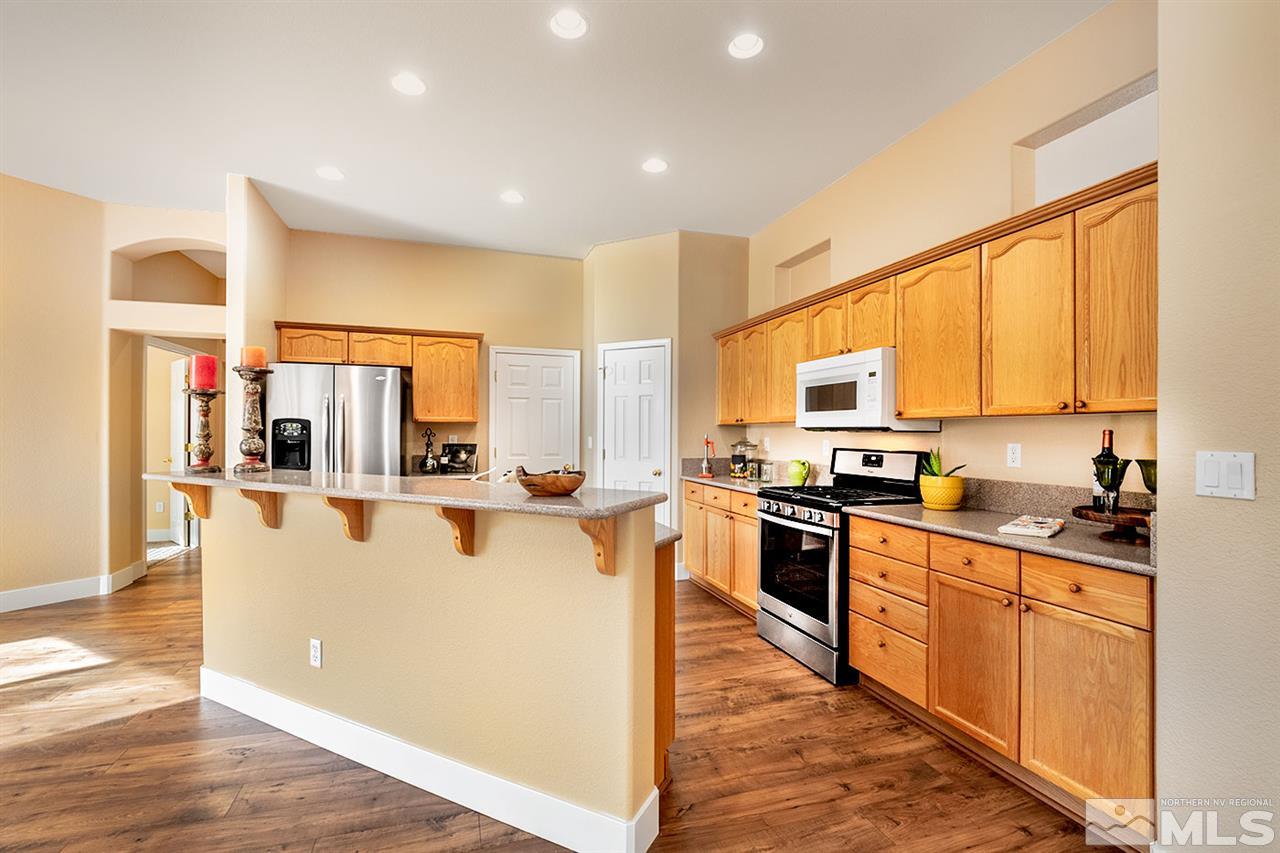 1726 Colavita Way Reno, NV 89521 - Photo 8 of 23 a kitchen with stainless steel appliances granite countertop a stove top oven a sink a refrigerator white cabinets and wooden floor