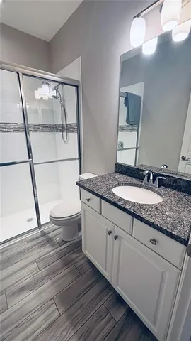 a bathroom with a granite countertop sink toilet a mirror and vanity