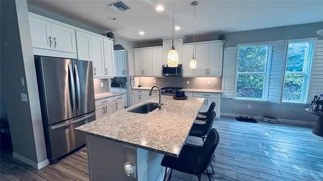 a kitchen with stainless steel appliances granite countertop a refrigerator a stove a sink a dining table and chairs