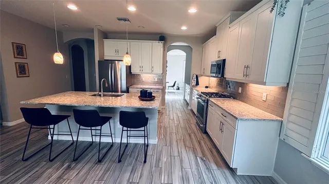 a kitchen with stainless steel appliances kitchen island granite countertop wooden floors and wooden cabinets