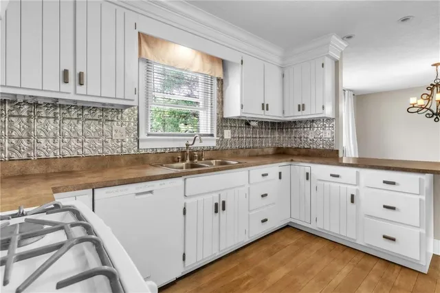 a kitchen with granite countertop white cabinets white appliances a sink and a large window