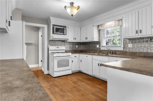 a kitchen with granite countertop white cabinets and white appliances