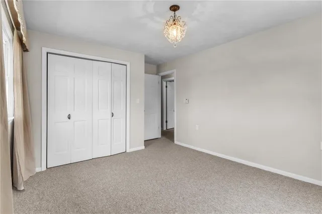 an empty room with a chandelier fan and closet area