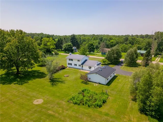 an aerial view of a house with swimming pool a yard and a large tree