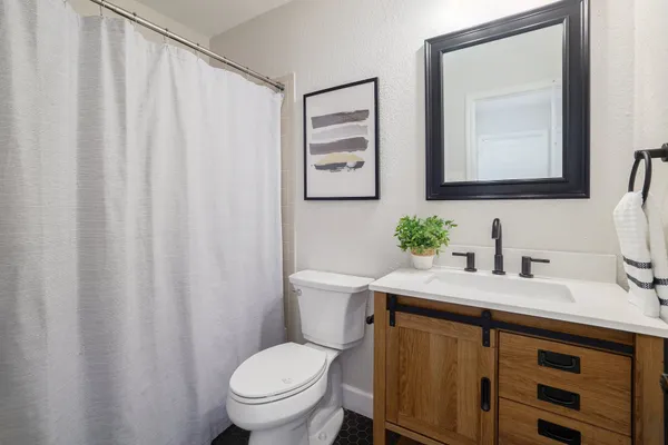 a bathroom with a granite countertop sink vanity mirror and toilet