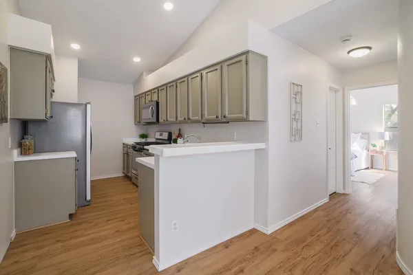 a kitchen with a refrigerator a sink and wooden floor