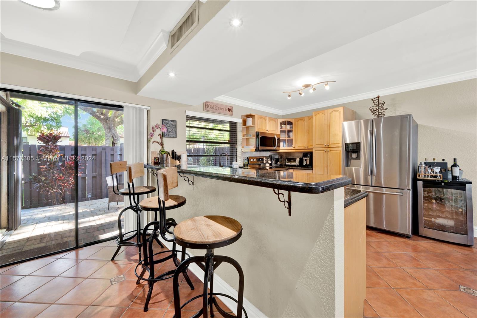 13339 Southwest 112th Terrace, Unit 504 Miami, FL 33186 - Photo 6 of 26 a kitchen with stainless steel appliances kitchen island granite countertop a refrigerator a stove a dining table and chairs with wooden floor