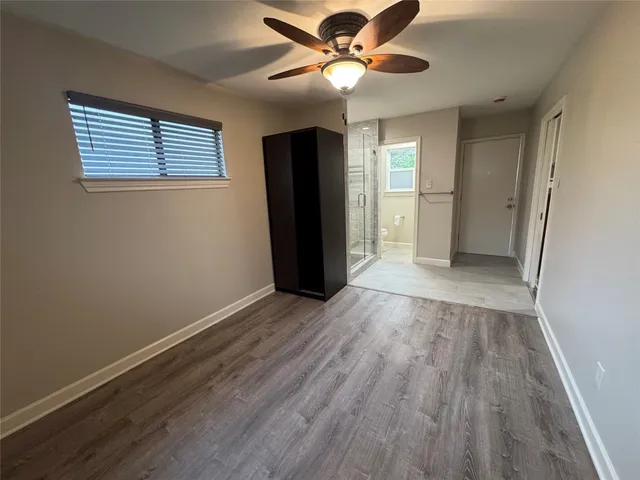 a view of an empty room with window and wooden floor