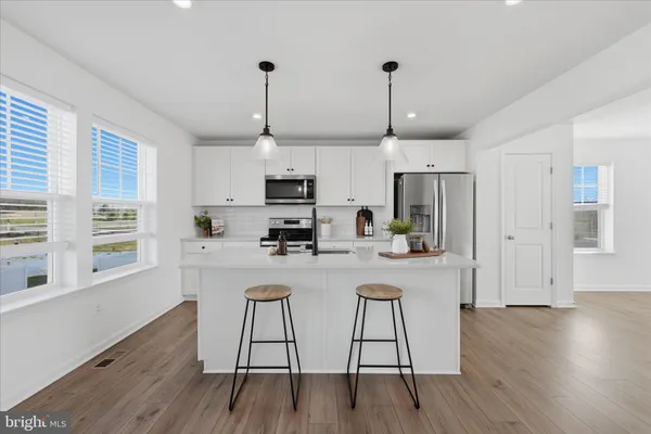 a kitchen with stainless steel appliances granite countertop a refrigerator a stove a sink dishwasher a microwave oven a stove with wooden floor