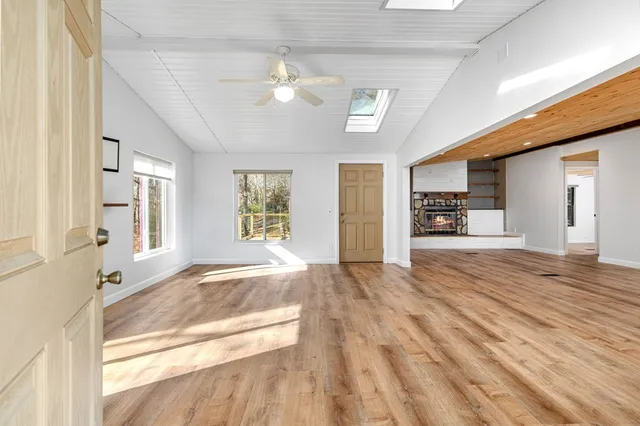 a view of an empty room and kitchen with wooden floor
