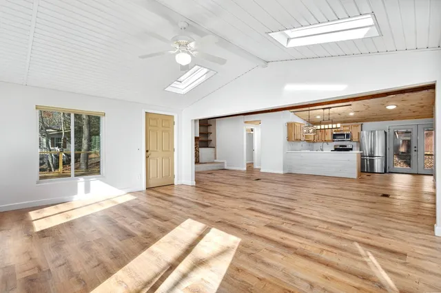 a view of an empty room with window and wooden floor