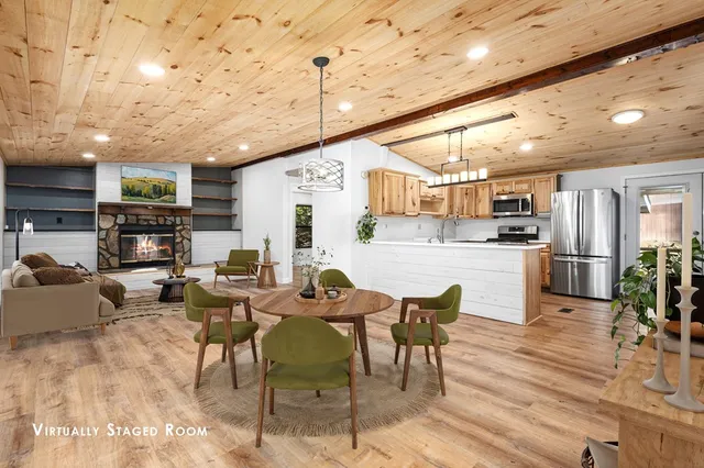 a living room with stainless steel appliances kitchen island granite countertop a table chairs microwave and sink