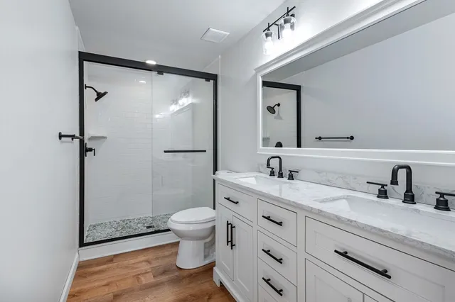 a bathroom with a granite countertop sink toilet a mirror a vanity and shower