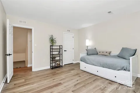 a spacious bedroom with a bed and wooden floor