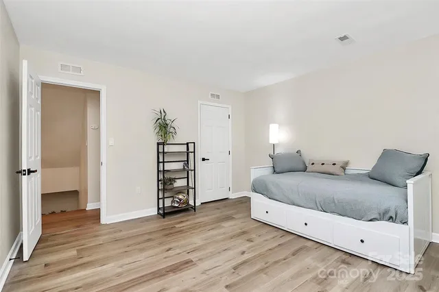a spacious bedroom with a bed and wooden floor