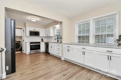 a kitchen with granite countertop white cabinets and wooden floor