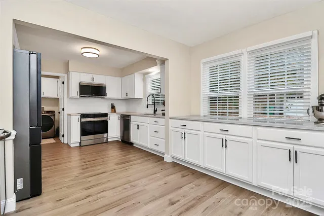 a kitchen with granite countertop white cabinets and wooden floor