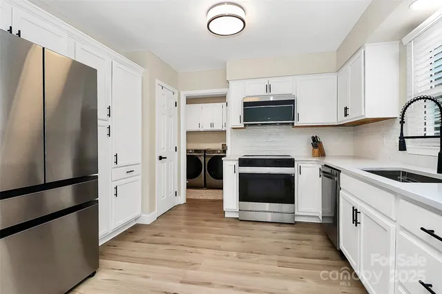 a kitchen with stainless steel appliances a refrigerator a stove top oven a sink and cabinets