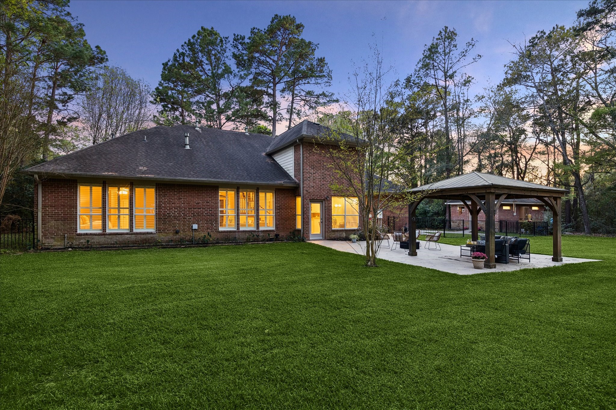 14530 Millhouse Road Pinehurst, TX 77362 - Photo 33 of 46 Rear elevation showcasing a spacious backyard with mature trees and extended patio, creating a seamless connection to outdoor living areas.