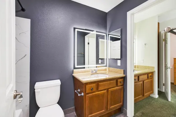 a bathroom with a granite countertop toilet sink and mirror