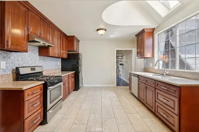 a kitchen with stainless steel appliances granite countertop a stove a sink and a refrigerator