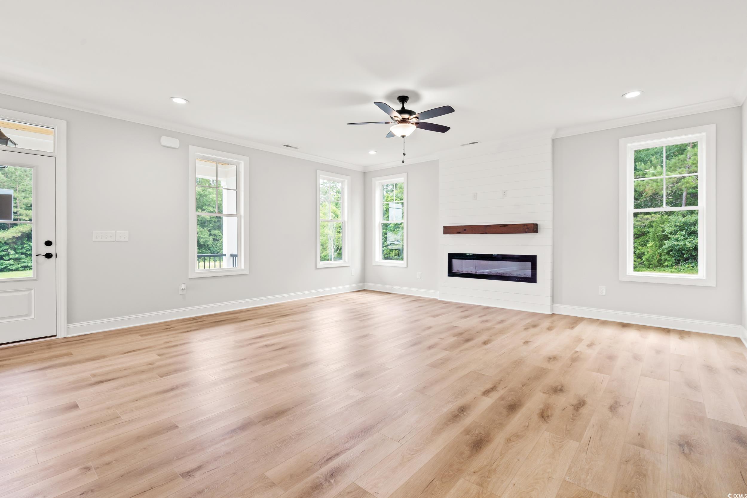 805 Commanders Island Road Georgetown, SC 29440 - Photo 6 of 40 Unfurnished living room featuring crown molding, recessed lighting, light wood-style flooring, ceiling fan, and a glass covered fireplace