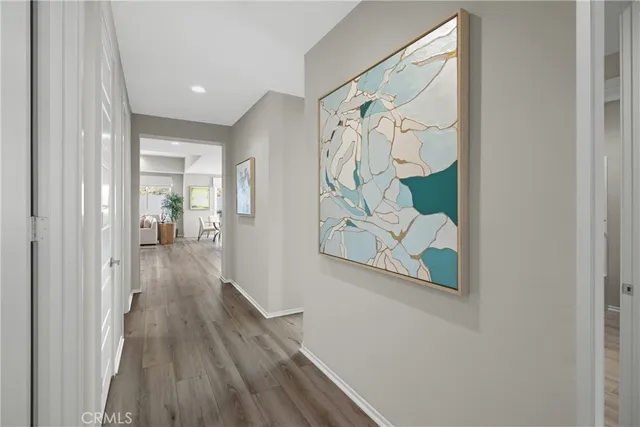 a view of a hallway with wooden floor and a bathroom