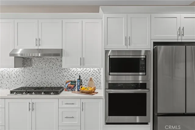 a kitchen with granite countertop white cabinets and stainless steel appliances