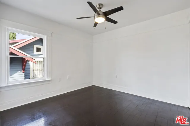 an empty room with wooden floor closet and windows
