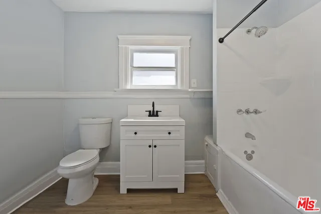 an empty room with wooden floor and a ceiling fan