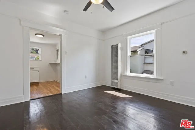 an empty room with wooden floor and ceiling fan
