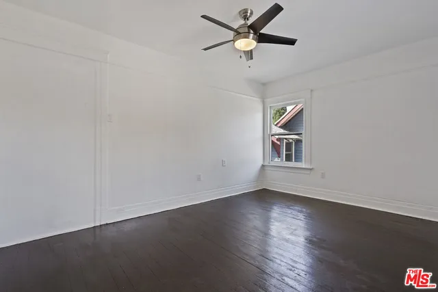 a view of an empty room with window and wooden floor