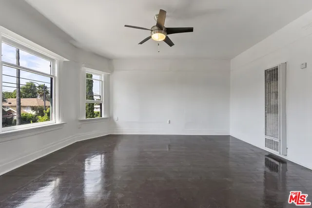 a view of an empty room with window and wooden floor