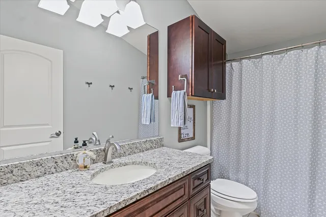 a bathroom with a granite countertop sink a toilet and a mirror