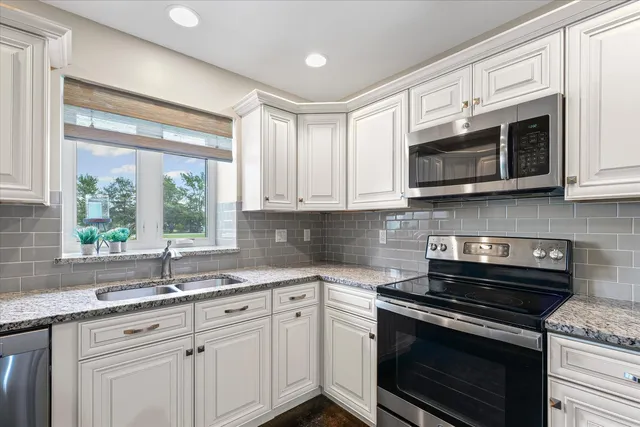 a kitchen with stainless steel appliances granite countertop white cabinets granite counter tops and a window