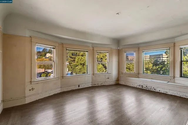 an empty room with fireplace wooden floor and windows
