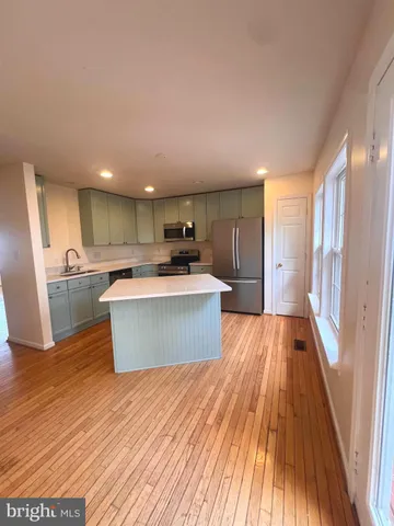 a large kitchen with stainless steel appliances wooden floors and wooden cabinets