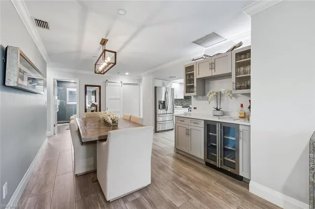 a living room with stainless steel appliances kitchen island hardwood floor and a sink