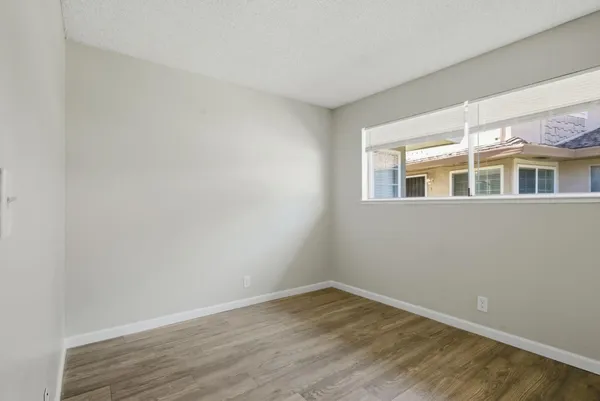 a view of empty room with wooden floor and fan
