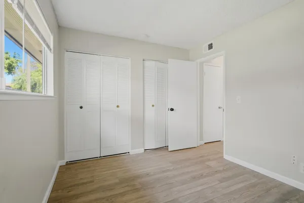 a view of an empty room with wooden floor and a window