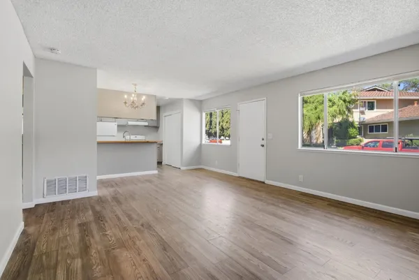 a view of empty room with kitchen and window